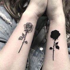 two matching tattoos with roses on their arms, one is black and the other is white