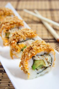 two pieces of sushi on a white plate with chopsticks next to it