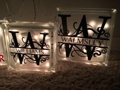 two glass blocks with lights on them that spell out the names of their respective families