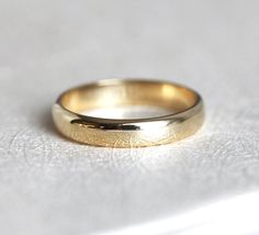 a gold wedding ring sitting on top of a white surface