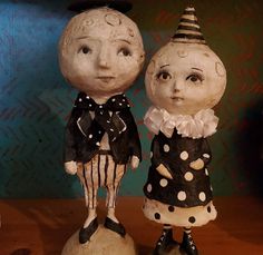 two ceramic figurines sitting on top of a wooden table