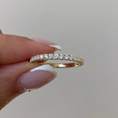 a woman's hand holding a yellow gold ring with three diamonds on the band