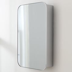 a mirror mounted to the side of a wall next to a white wall with a window