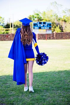 a woman in a blue graduation gown walking across a field