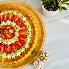 a pie with strawberries and other toppings sitting on top of a wooden cutting board