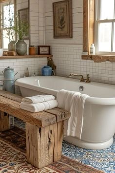 a white bath tub sitting next to a wooden bench in a bathroom under a window