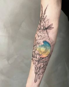 a woman's arm with flowers on it and the sun in the background, which is