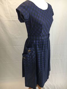 "This dress has me a little confused. 90% sure it's a 50's reproduction, because it's in perfect condition, but size on label say's 14, and fits like a modern 6. Non the less, it is charming! I love the overlapping pockets with big gold buttons. Color is like a blueish-purple. I would like to pair this with tie-up sandals and a ponytail! Excellent condition! Measurements are taken flat, so please double: Bust 18\" Waist 14\" Length 42\" All sales are final/I welcome questions!" Vintage A-line Dress With Buttons, Classic A-line Vintage Dress With Button Closure, 1950s Style Fitted Dress With Buttons, 1950s A-line Dress With Buttons, Fitted Retro Vintage Dress With Button Closure, Retro A-line Dress With Button Closure, 1950s Style Knee-length Dress With Button Closure, Retro Vintage Dress With Buttons For Daywear, 1950s Style Lined Dresses For Daywear