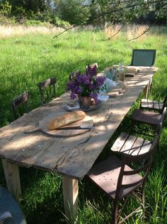 a wooden table sitting in the middle of a grass covered field with flowers on it