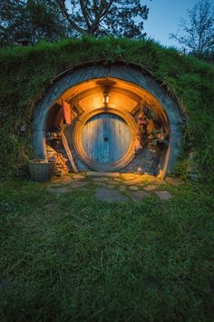 an image of a hobbot house in the woods at night with lights on