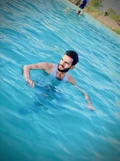 a man swimming in a pool with blue water