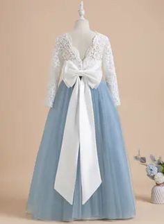 a blue and white flower girl dress with a large bow at the waist, on display