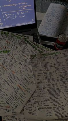 several pieces of paper sitting on top of a table next to a laptop computer and notebook