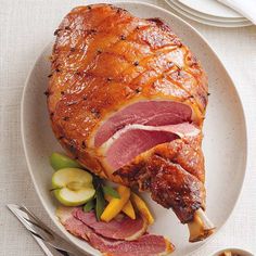 a ham is on a white plate with silverware