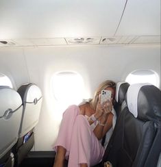 a woman sitting in an airplane looking at her cell phone