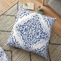 a blue and white pillow sitting on top of a rug next to a chair with a book