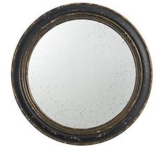 a round mirror sitting on top of a white wall