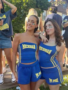 two girls in blue cheerleader outfits posing for the camera with their hands on their hips