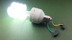 a light bulb with some wires attached to it on a green surface and one yellow wire is plugged in