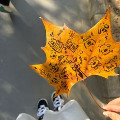 a person holding up a yellow leaf with writing on it