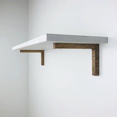 a white shelf with two wooden brackets on it