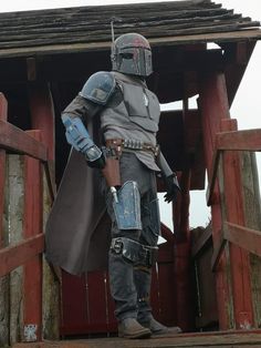 a man dressed as boba fett standing on top of a wooden structure