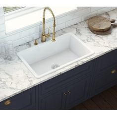 a white kitchen sink sitting under a window next to a faucet and counter top