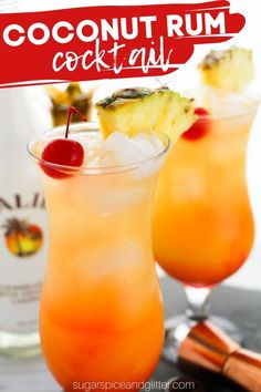 two cocktails with pineapple and cherries on the rim, next to a bottle of coconut rum