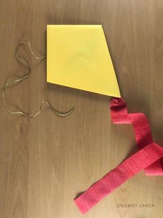 a piece of yellow paper with pink tape attached to it on top of a wooden table