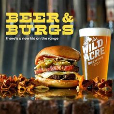 there is a large hamburger next to a glass of beer