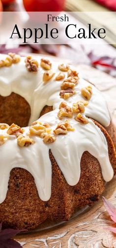 a fresh apple cake with white icing and walnuts on top is sitting on a plate