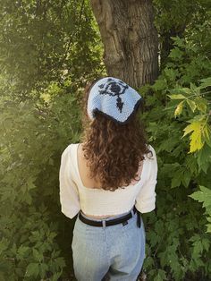 a woman standing in front of a tree wearing a blue and white knitted hat