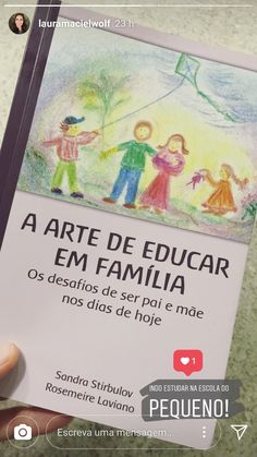 a person holding up a book with an image of children flying a kite in the sky