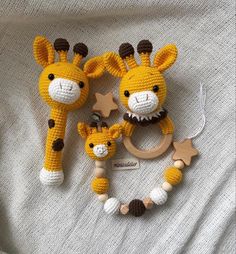 two crocheted giraffes and a baby pacifier on a bed