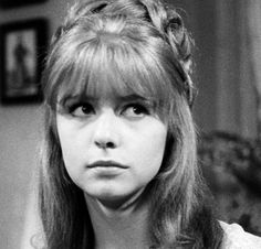 an old black and white photo of a woman with long hair in a messy hairstyle