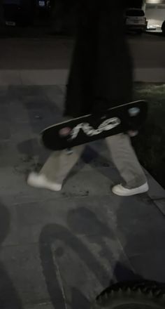 a person walking down the street with a skateboard in their hand and one foot on the ground