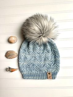 a knitted hat with two seashells next to it on a white background