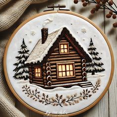 a small wooden cabin with snow on the roof and lights in the windows at night