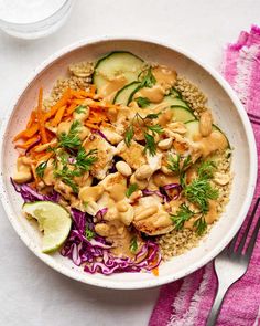 a white bowl filled with chicken, rice and veggies next to a fork