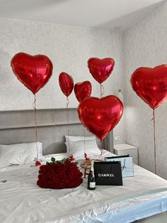 red heart shaped balloons are on the bed