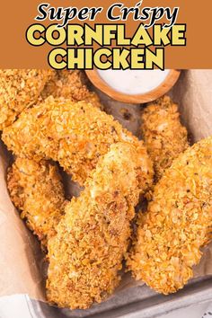 chicken tenders in a tray with ranch dressing and dipping sauce on the side, text super crispy cornflake chicken