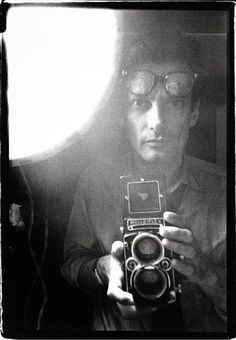 a man taking a selfie in front of a mirror with an old fashioned camera