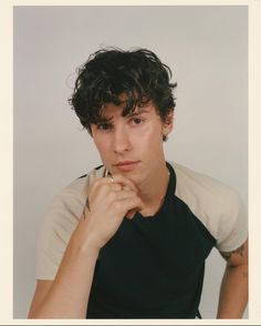 a young man poses for a photo with his hand on his chin and looking at the camera