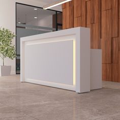 an empty white reception counter in front of a wooden paneled wall and potted plant