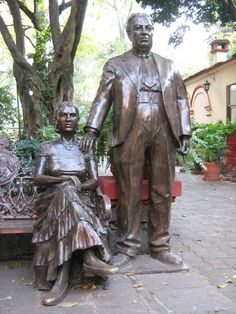 a statue of a man and woman sitting next to each other on a park bench