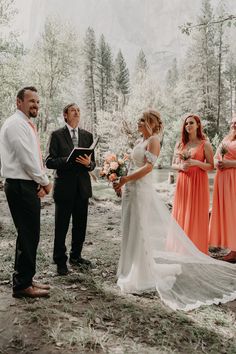 a bride and groom are getting married in the woods with their wedding party looking on