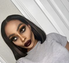 a woman with dark lipstick and makeup looks at the camera while standing in front of a white door