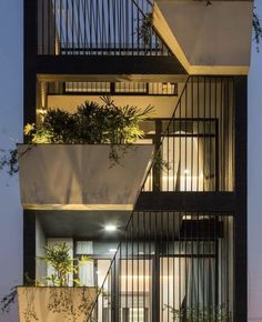 an apartment building with planters on the balconies and lights above it at night