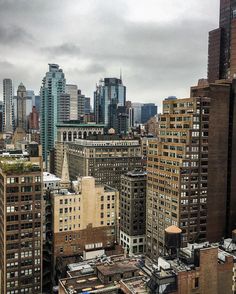 the city is full of tall buildings and skyscrapers under a cloudy sky with dark clouds