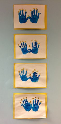 three handprints are hanging on the wall in front of two yellow and white frames